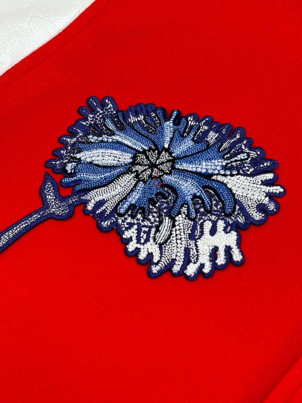 Blue embroidered floral patch on red varsity jacket front