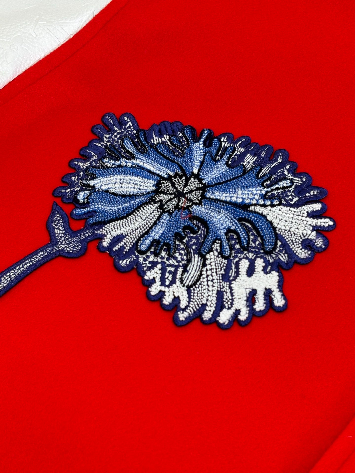 Blue embroidered floral patch on red varsity jacket front
