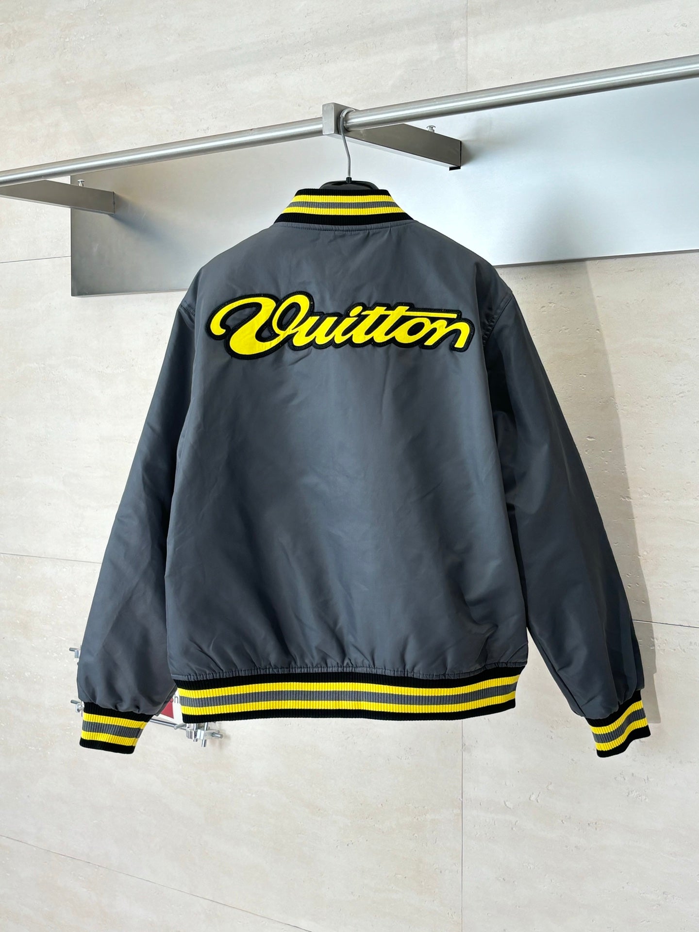 Louis Vuitton bomber jacket, dark gray back view with yellow logo and striped hem