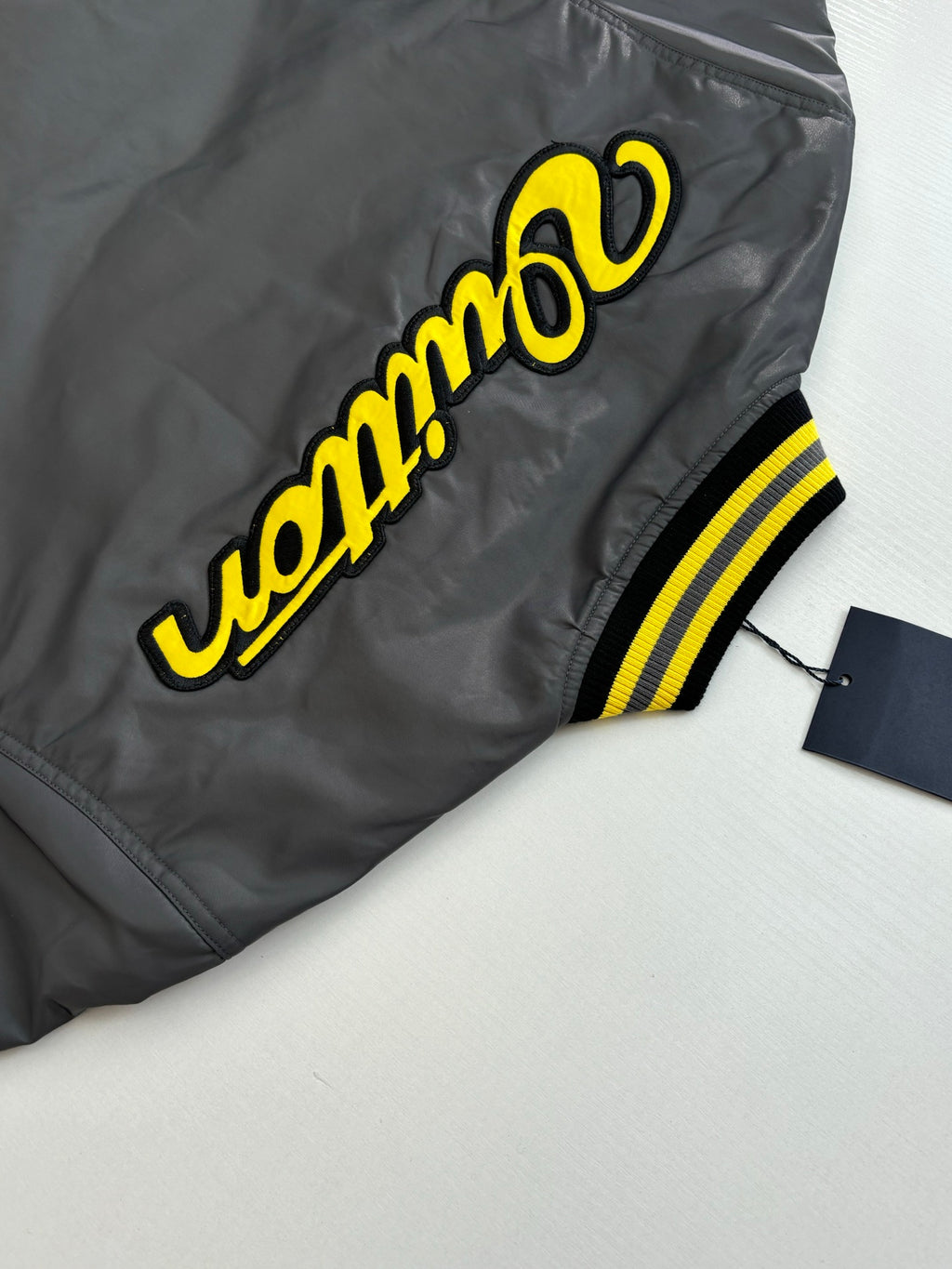 Louis Vuitton bomber jacket side view with yellow logo lettering and ribbed striped trim