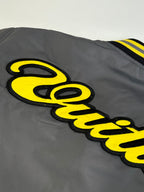 Long jacket sleeve with yellow embroidered logo on dark gray fabric