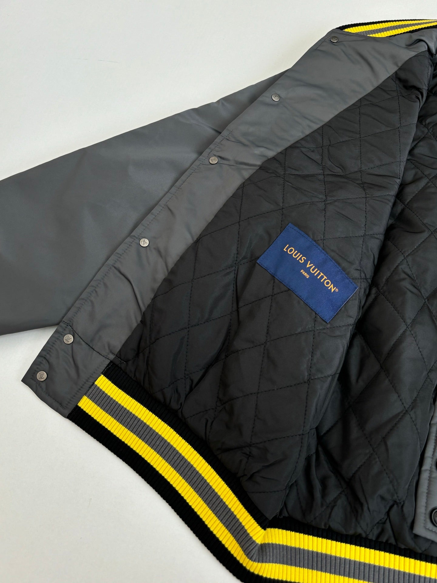 Louis Vuitton bomber jacket quilted side view with blue tag and yellow ribbed stripe trim