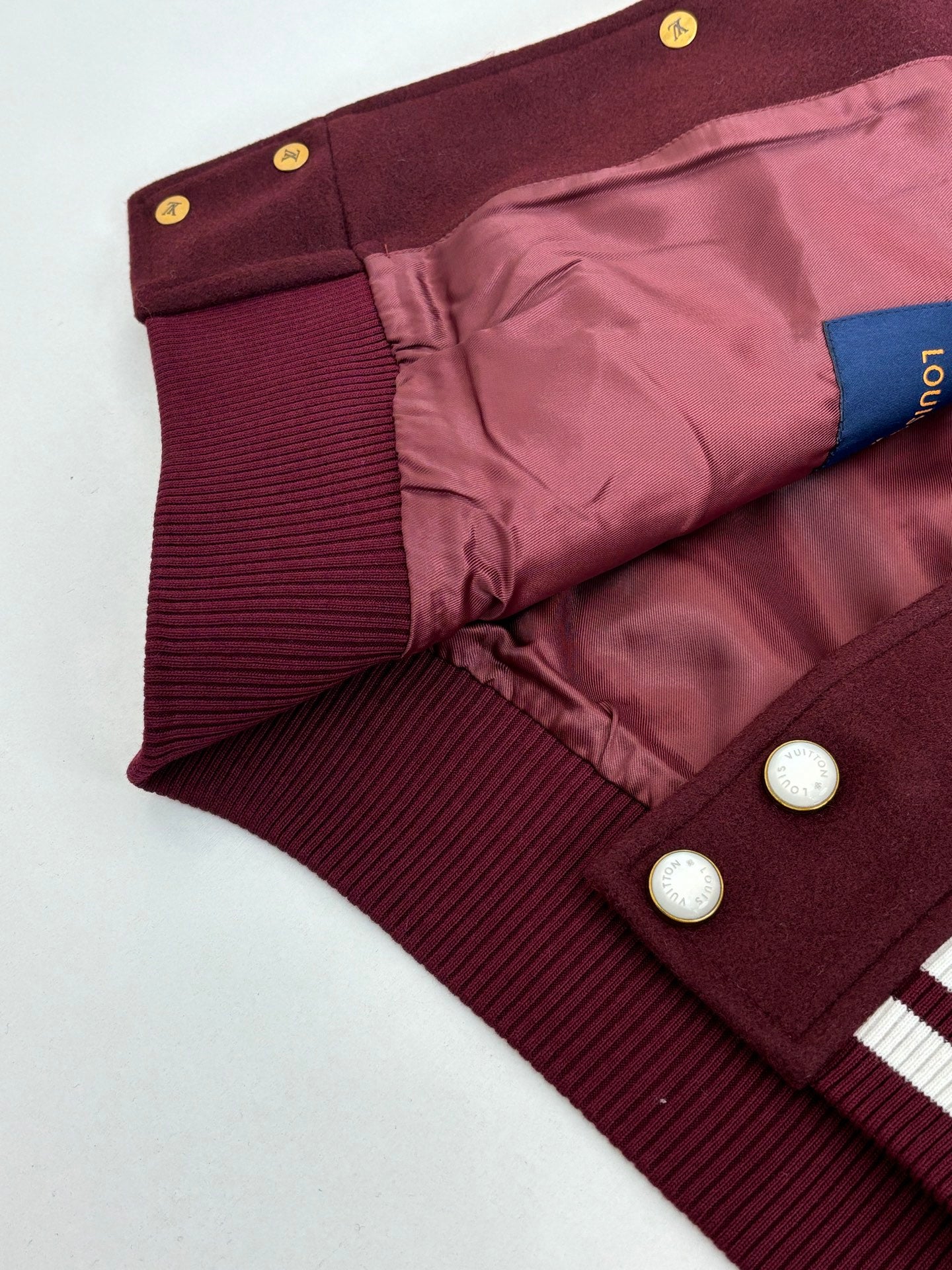 Inside view of burgundy varsity jacket lining with ribbed panels and snap buttons