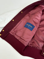 Inside view of burgundy jacket with pink lining and blue brand patch near cuff