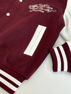 Close-up of burgundy varsity jacket sleeve stripe panel and front pocket/patch detail