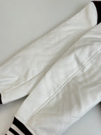 Close-up of white sleeve fabric with ribbed cuff and burgundy stripe trim