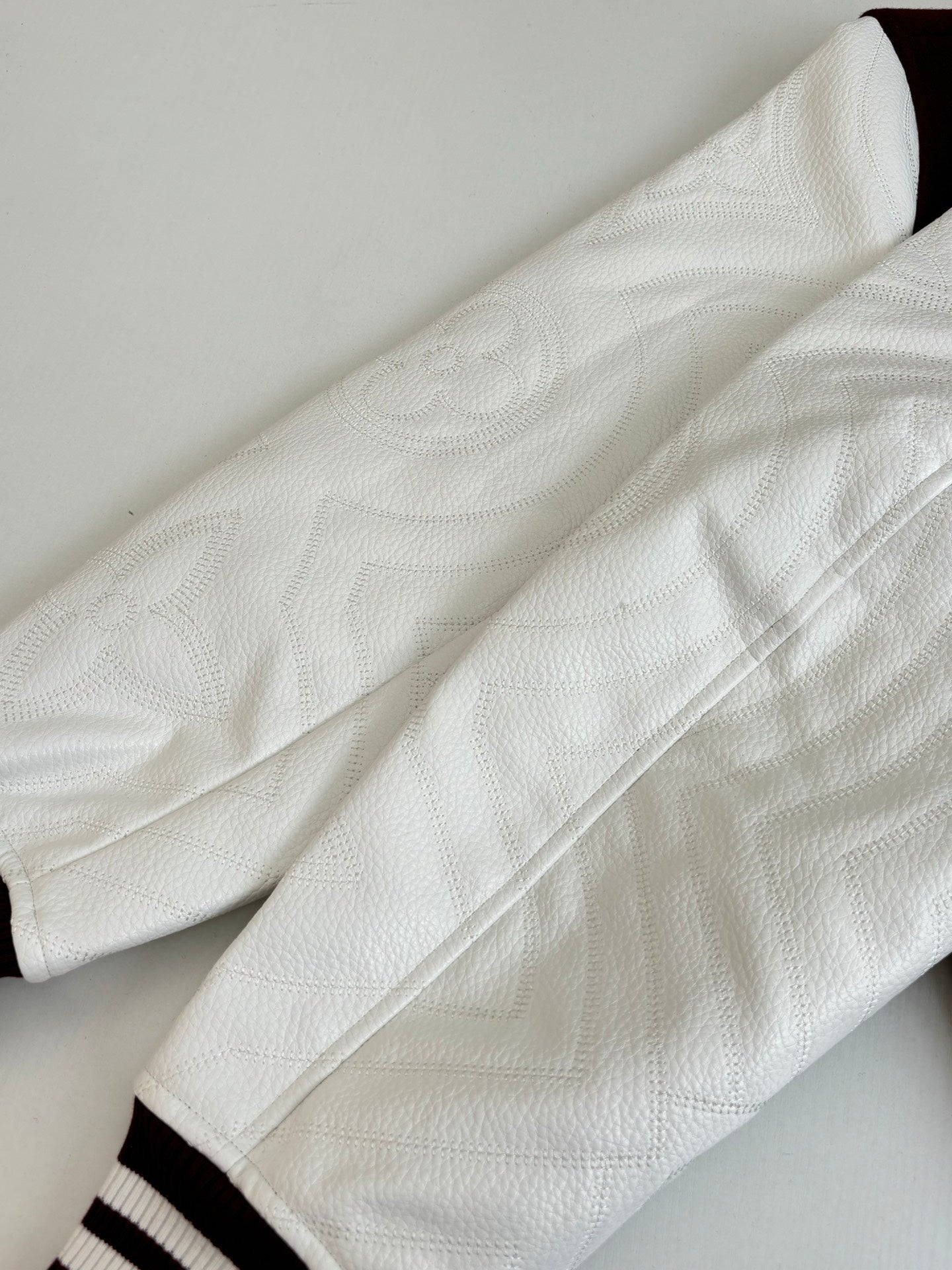 Close-up of white sleeve fabric with ribbed cuff and burgundy stripe trim