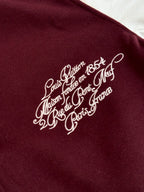 Close-up of white script logo on burgundy varsity jacket chest