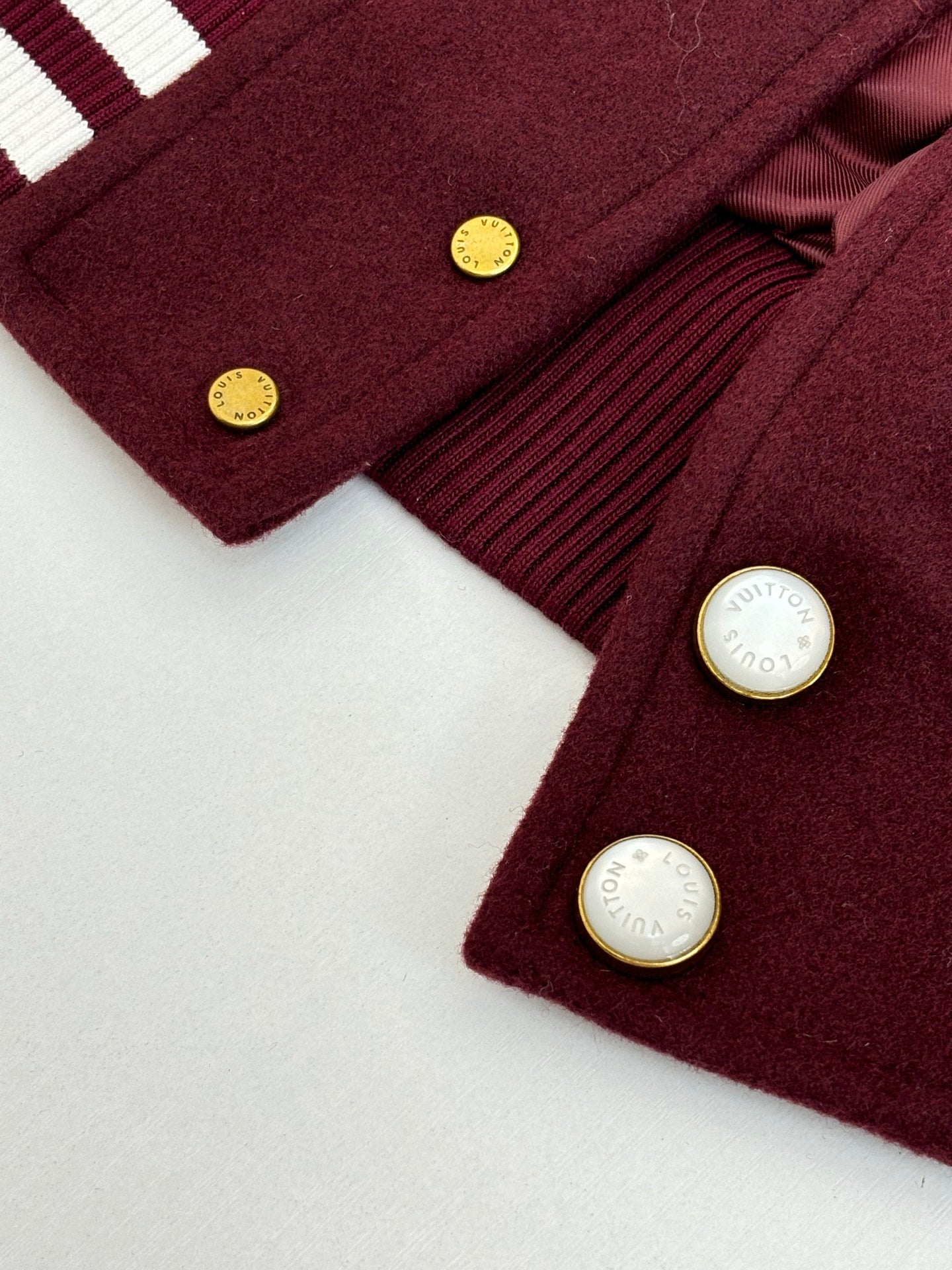 Close-up of burgundy jacket buttons with small gold-tone hardware and ribbed trim
