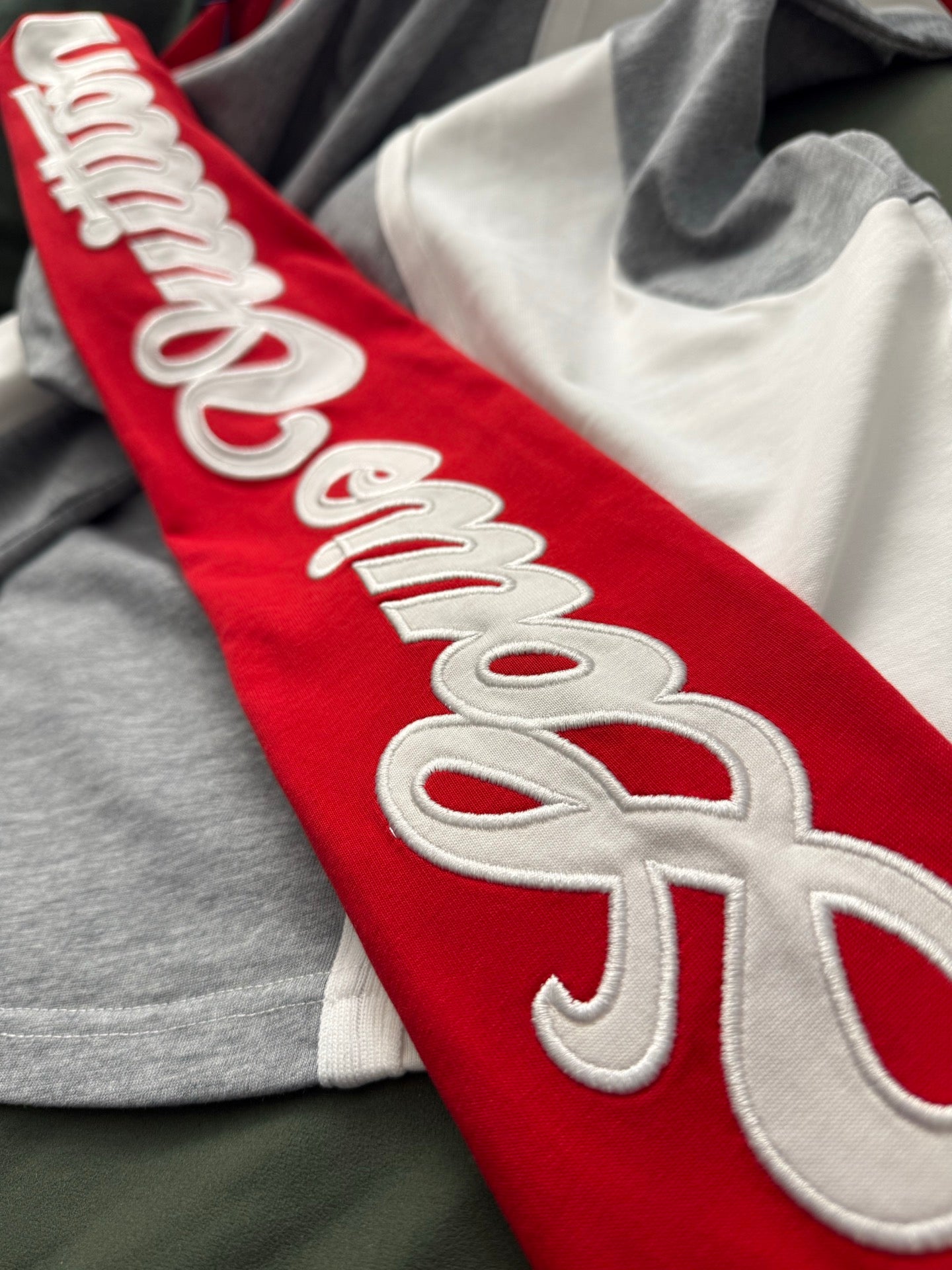 Red sleeve with white “Louis Vuitton” embroidery on a long-sleeve shirt