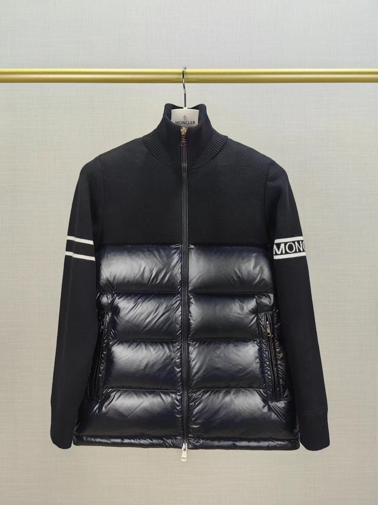 Down puffer jacket with knit sleeves, horizontal quilting, and front zipper on hanger