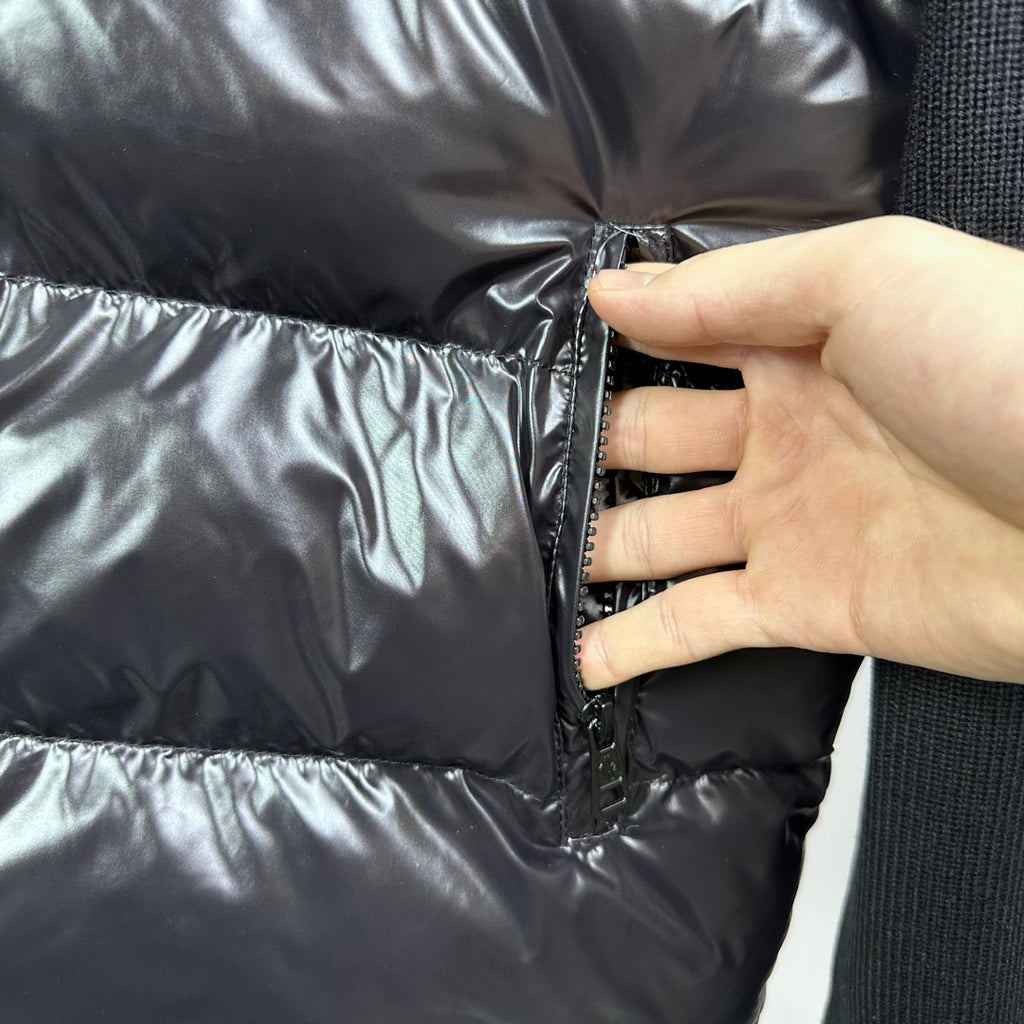 Hand adjusting front zipper on glossy down puffer jacket with knit sleeve