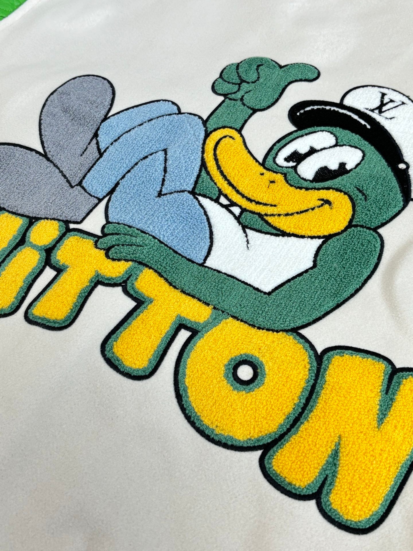 Louis Vuitton chest graphic on cream: smiling cartoon character with green hat and blue arms