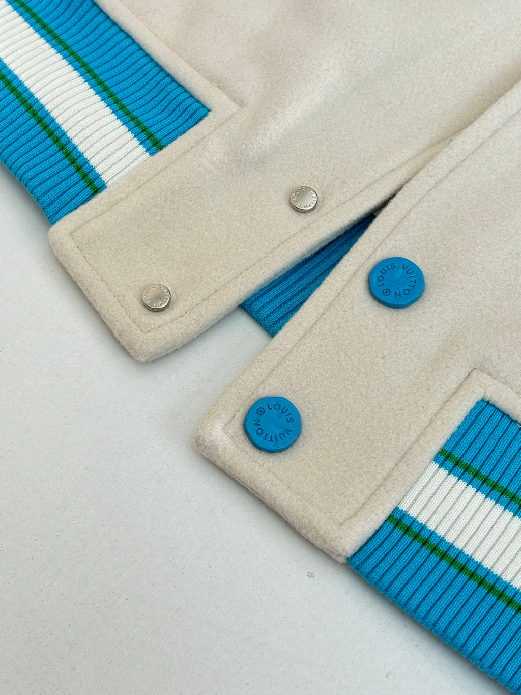 Louis Vuitton jacket close-up: snap buttons and blue ribbed trims on cream fabric