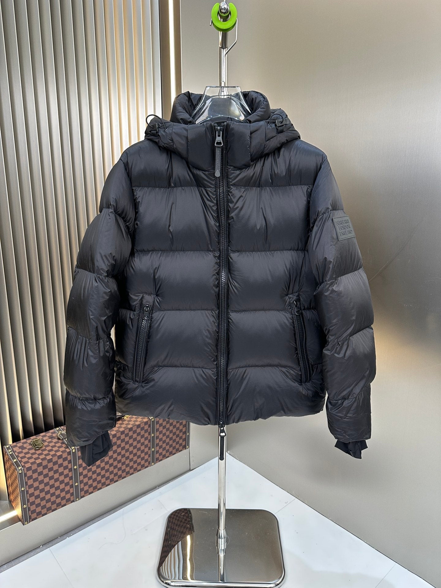 Long hooded puffer jacket, dark color, front view with padded shoulders and zipper