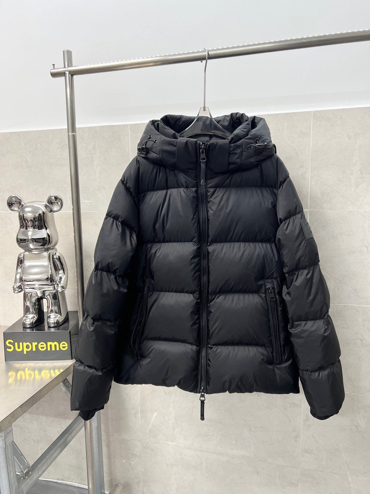 Long hooded puffer jacket, dark color, front view with drawcord hem and zipper