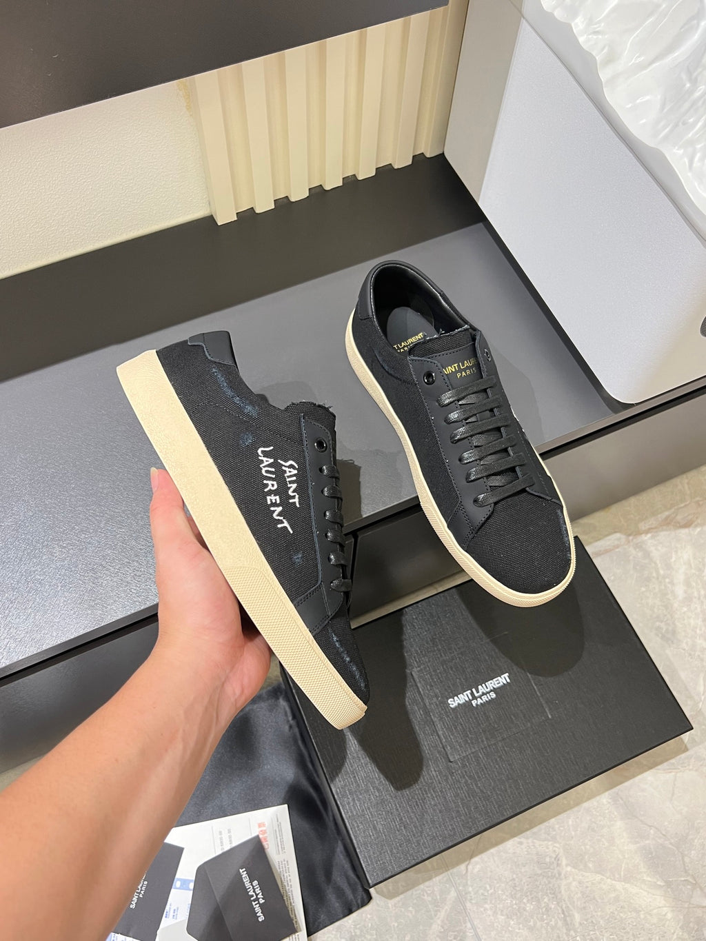 Saint Laurent unisex sneakers held in hand, dark gray with cream rubber sole