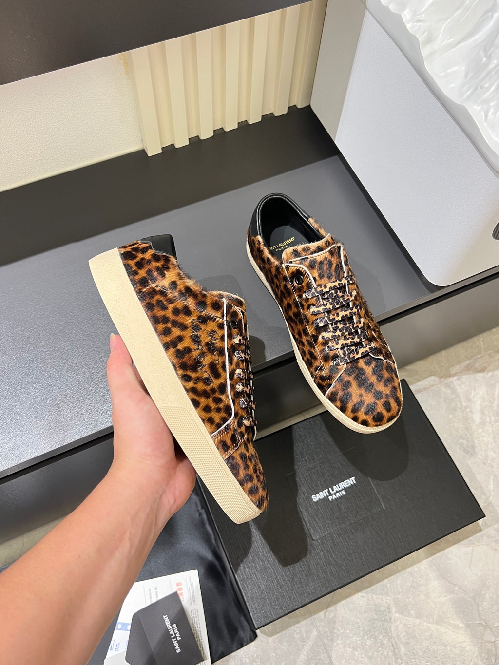YSL leopard-print lace-up sneakers held up, close-up of vamp and sole
