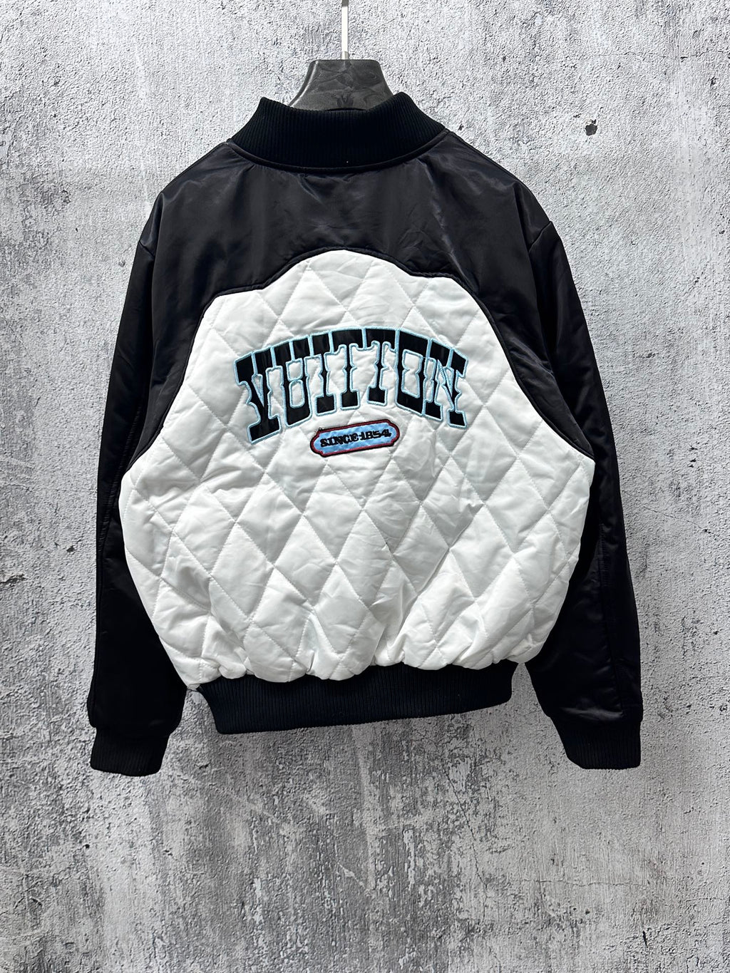 Black-and-white quilted jacket with back graphic, logo patch, and ribbed collar