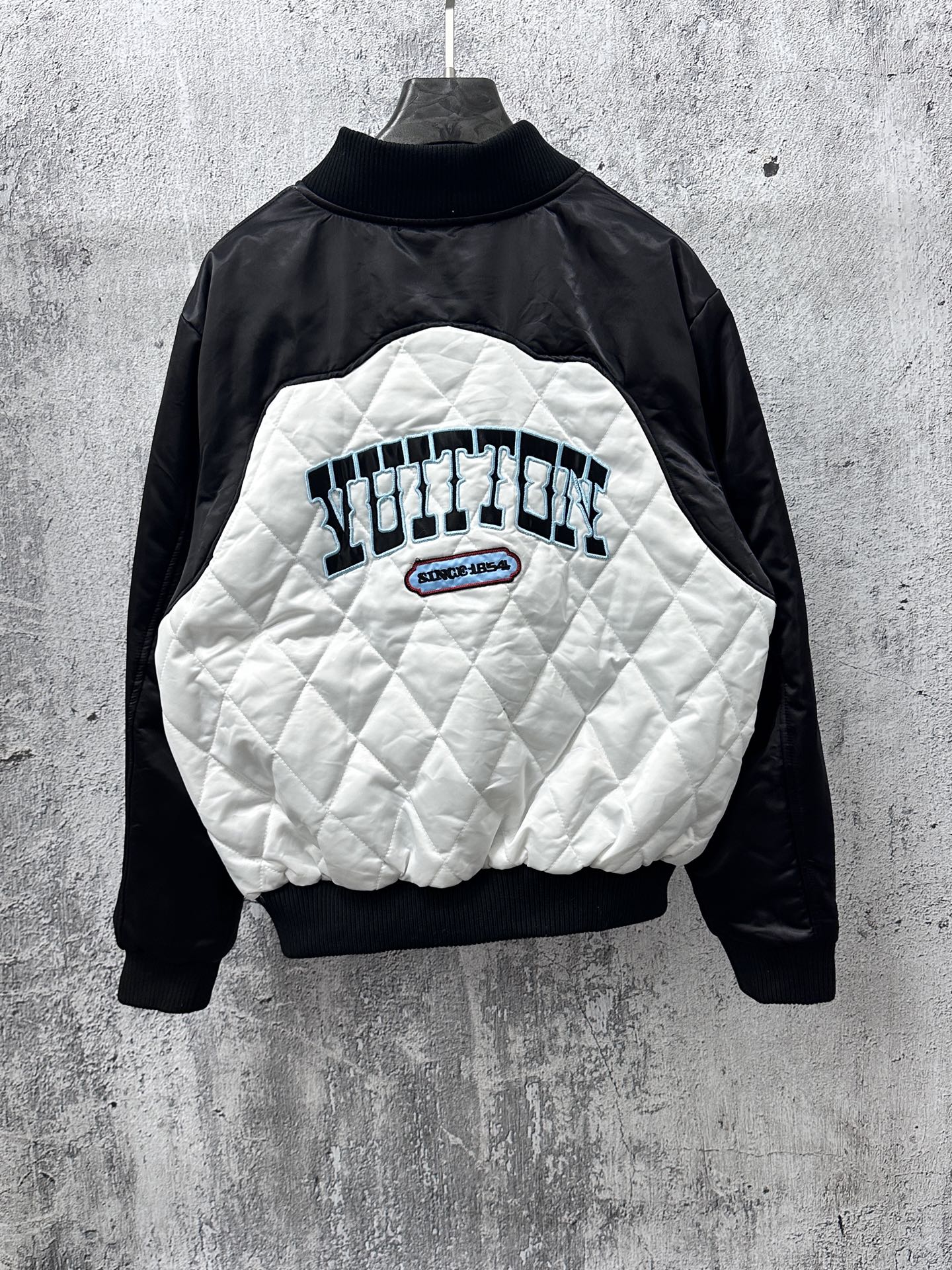 Black-and-white quilted jacket with back graphic, logo patch, and ribbed collar