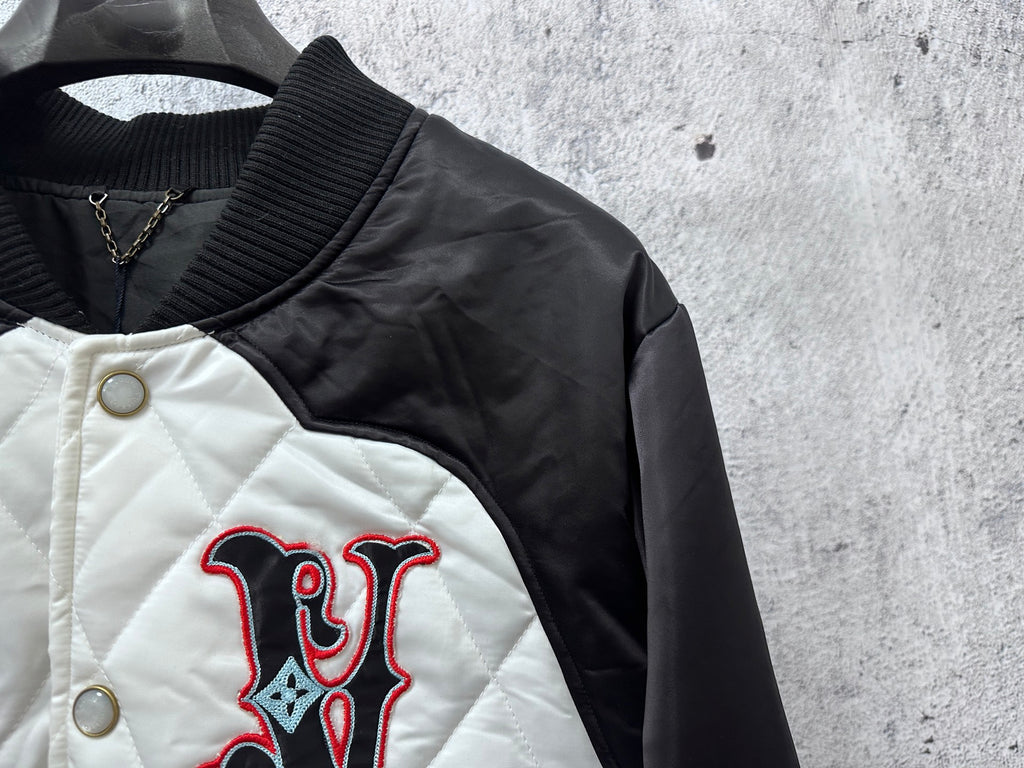 Quilted jacket close-up with embroidered red-and-black logo on white panel