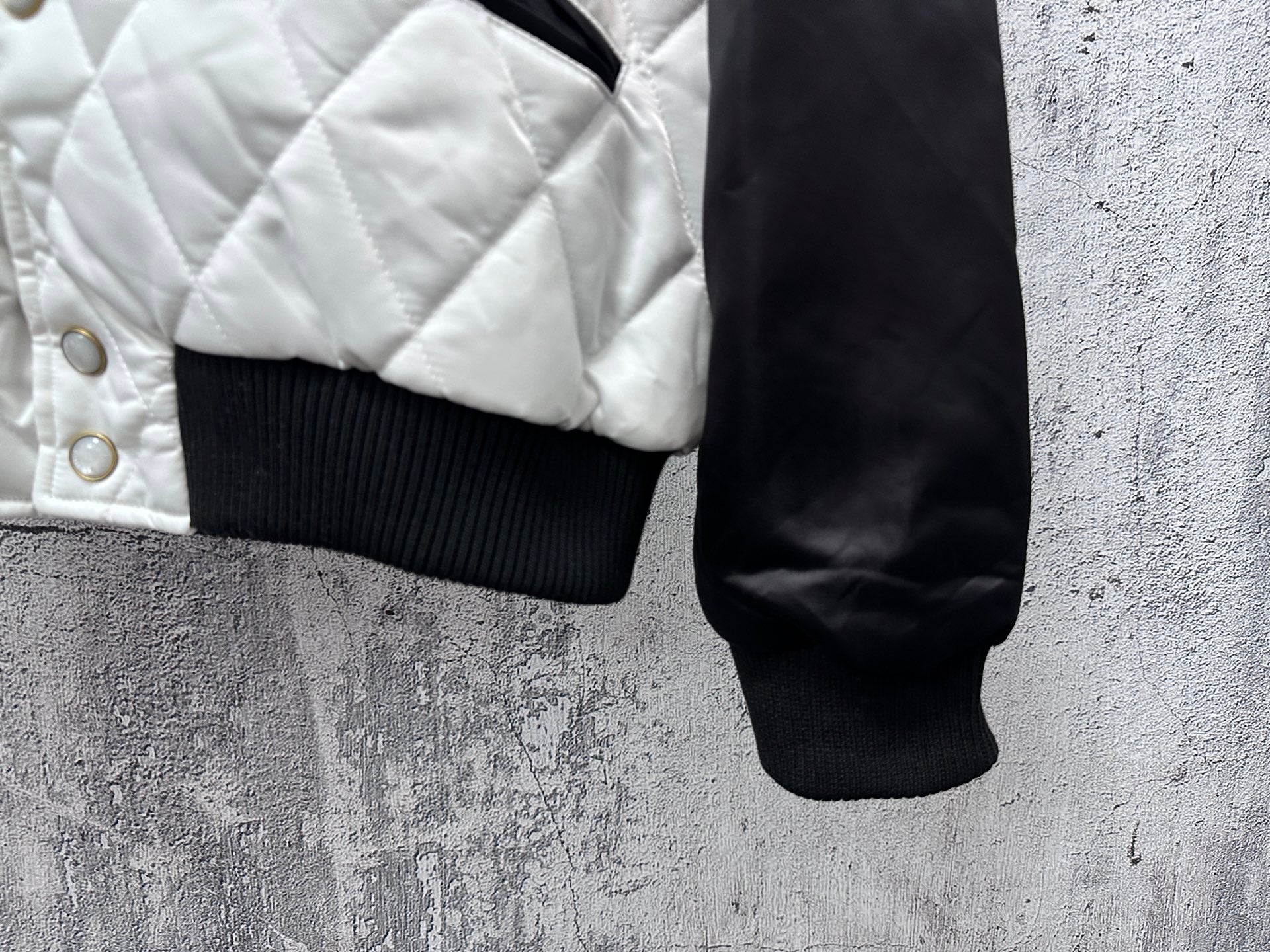 Quilted jacket hem with ribbed cuff and snap buttons on white panel