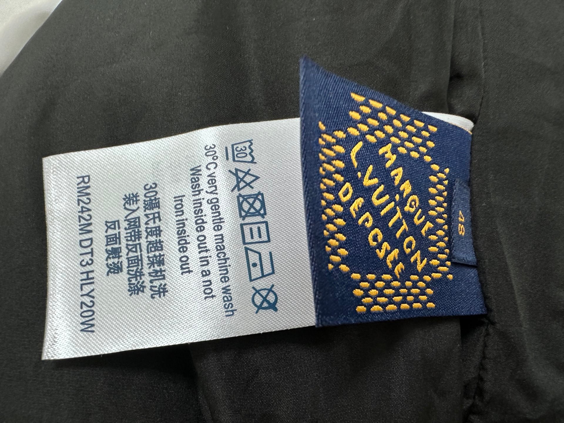 Clothing care label and size tag attached to dark garment