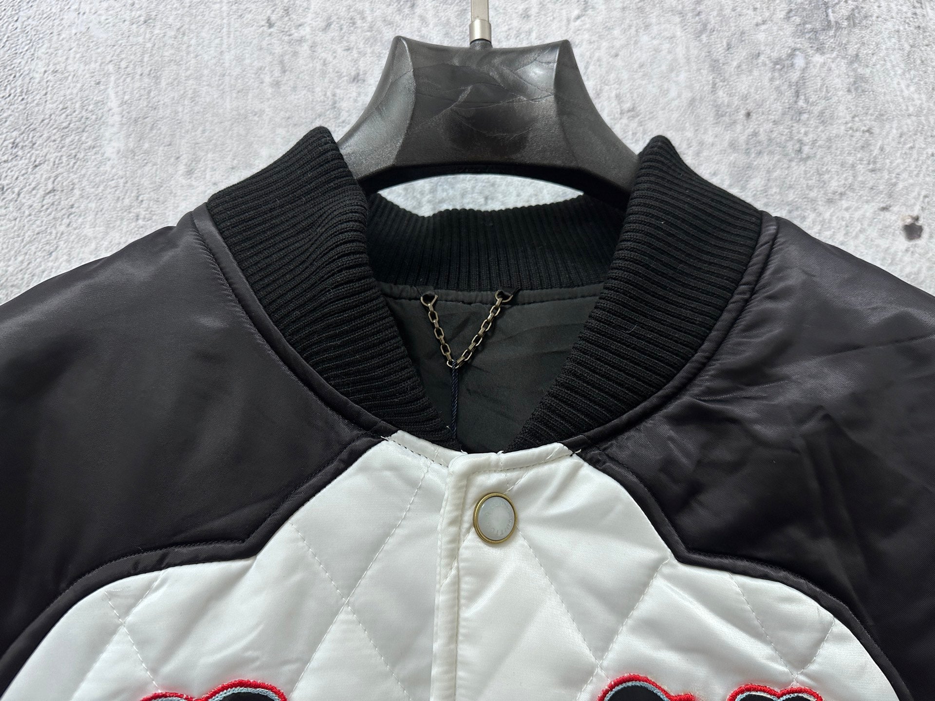Quilted jacket with ribbed collar, snap buttons, and small gold chain detail