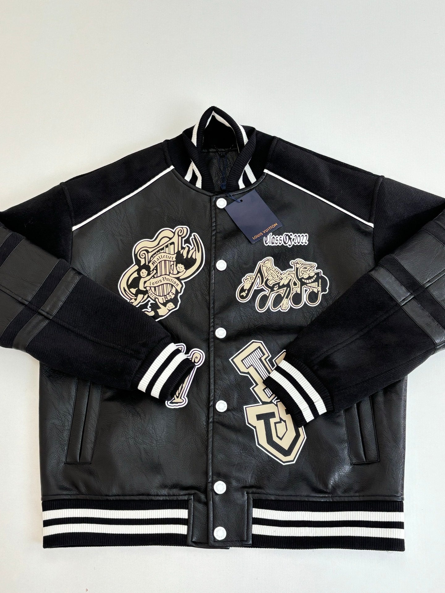 Louis Vuitton long jacket front view, black with cream crest patches and striped ribbing