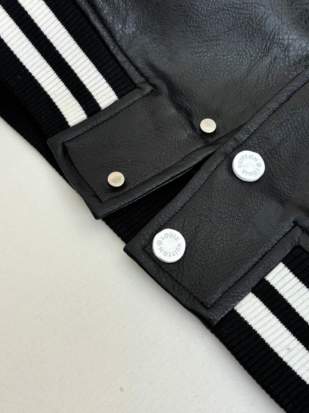 Louis Vuitton long jacket close-up, black fabric with snap placket and striped ribbed cuffs