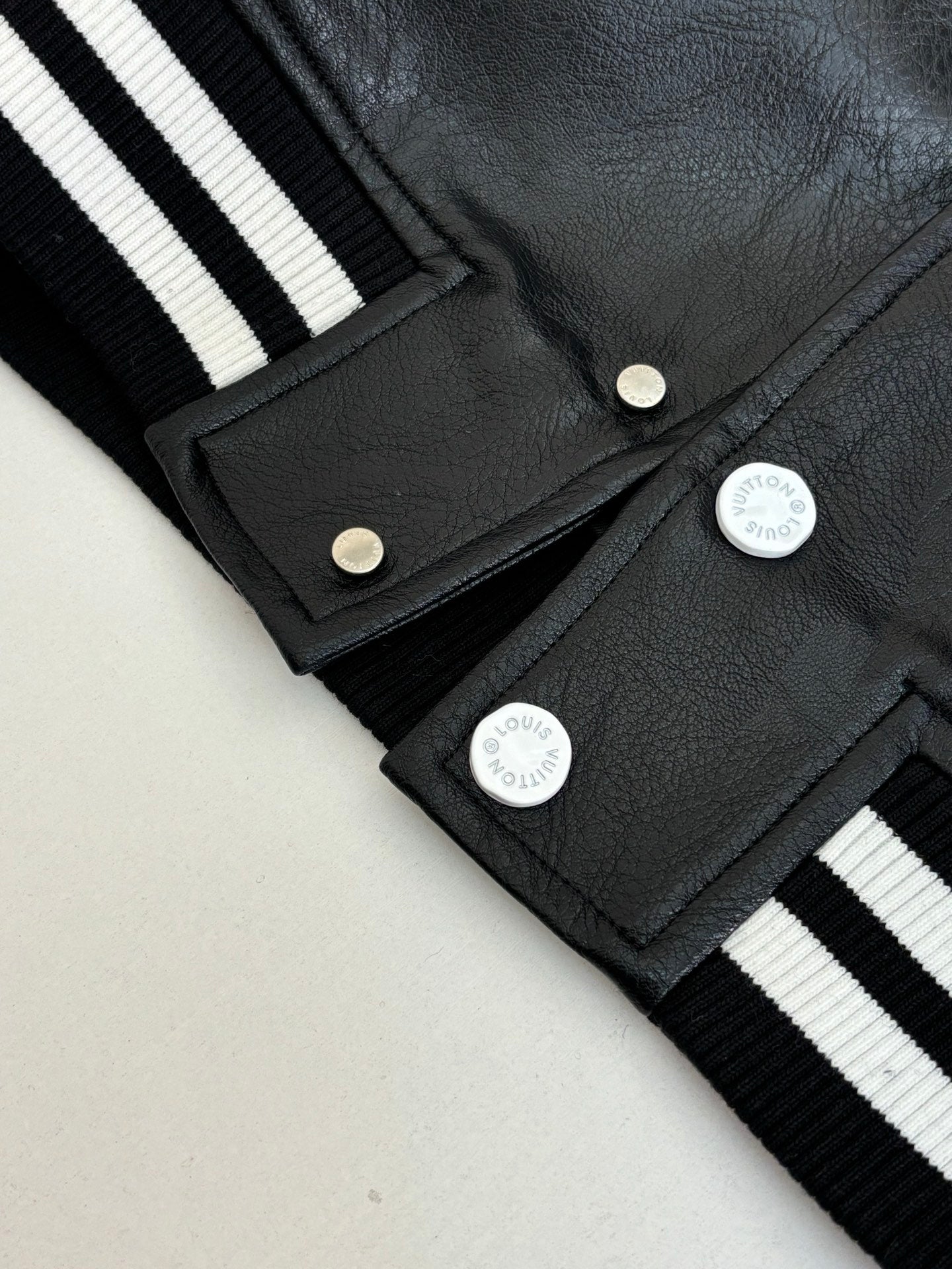 Louis Vuitton long jacket close-up, black fabric with snap placket and striped ribbed cuffs