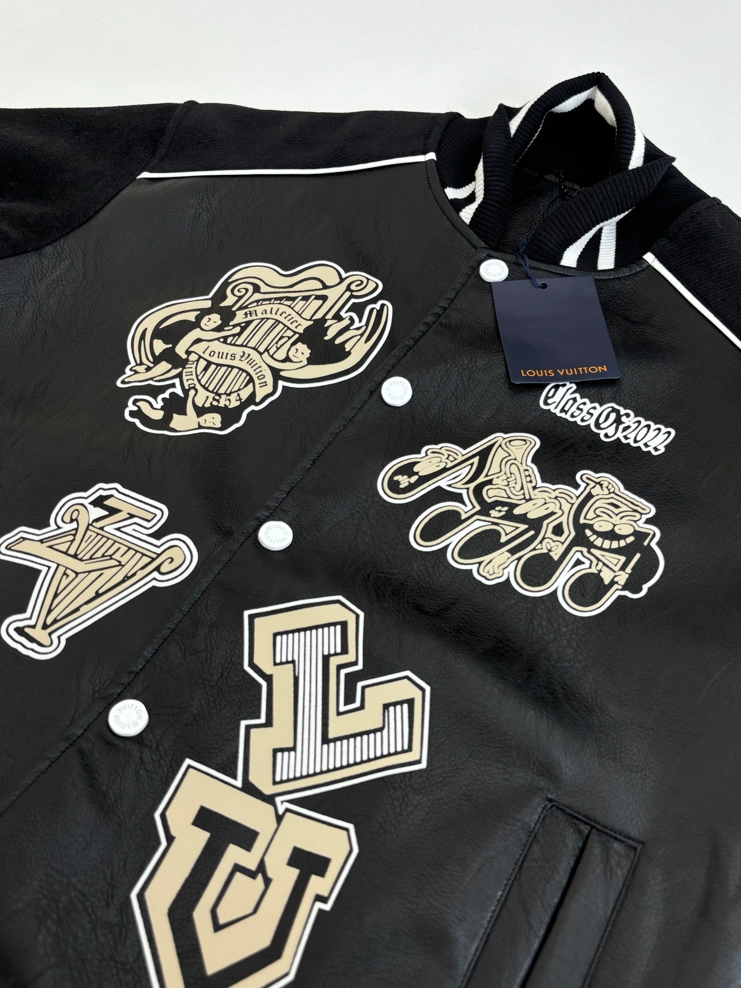 Louis Vuitton long jacket close-up, black with cream logo emblems and snap buttons