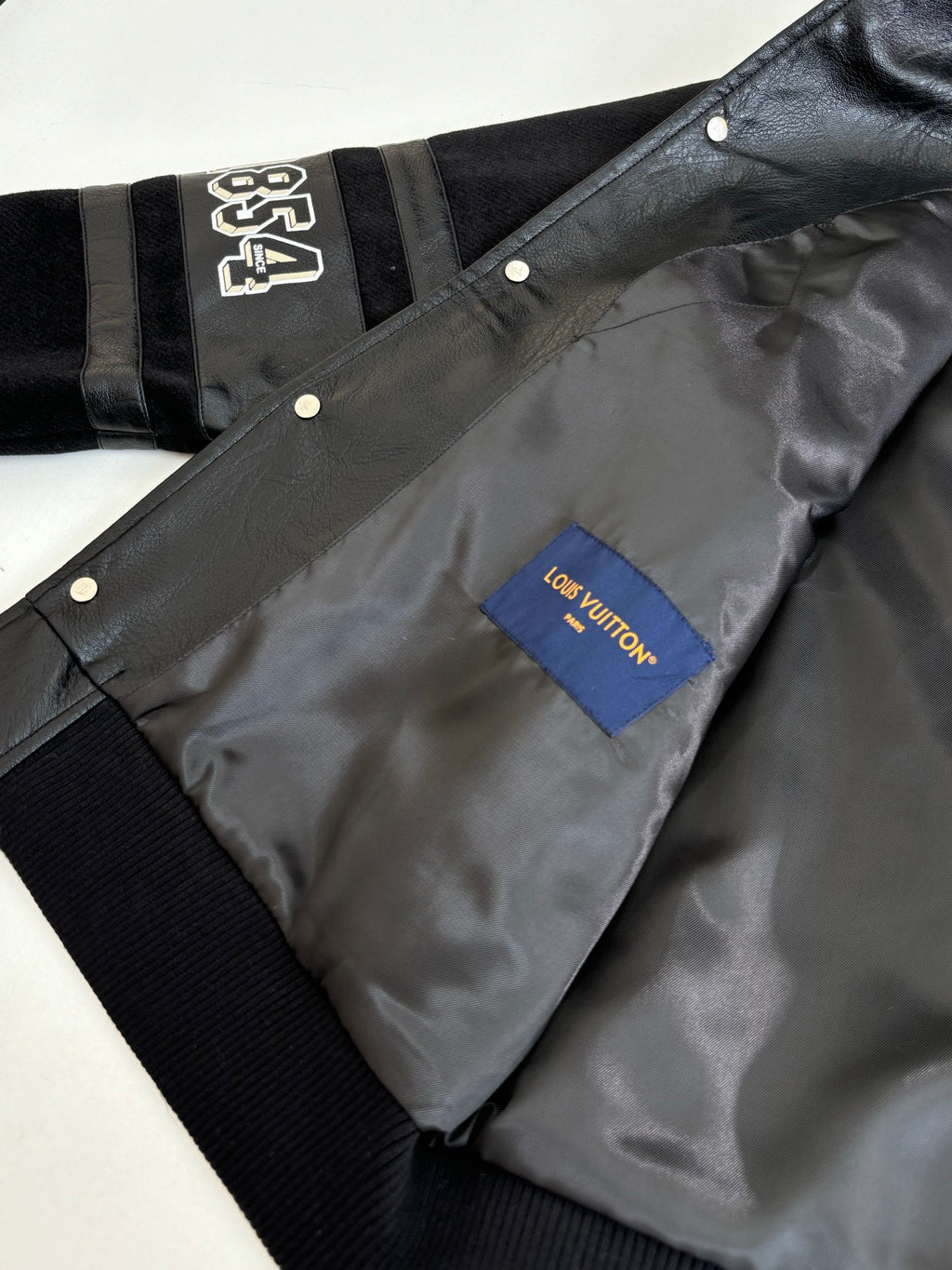 Black jacket with snap placket and gray interior lining, Louis Vuitton monogram patch