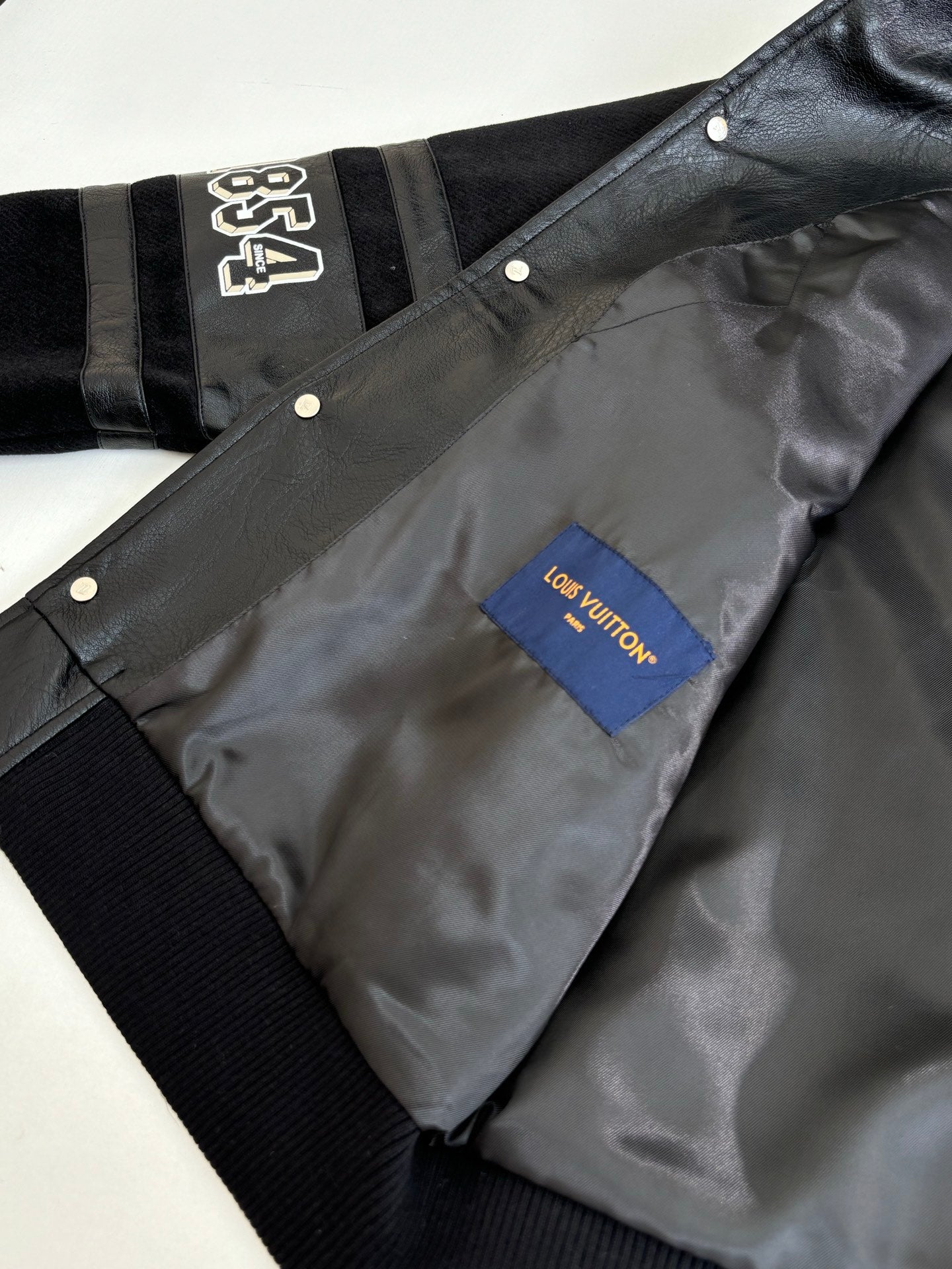 Black jacket with snap placket and gray interior lining, Louis Vuitton monogram patch