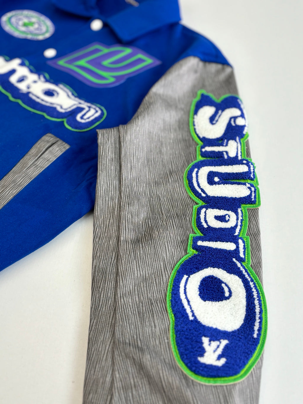 Long-sleeve top with grey body and blue emblem appliqué with green outline