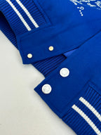 Blue varsity jacket close-up of snap buttons and striped ribbed cuffs