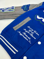 Blue varsity jacket close-up with cursive embroidery, striped ribbing, snap buttons