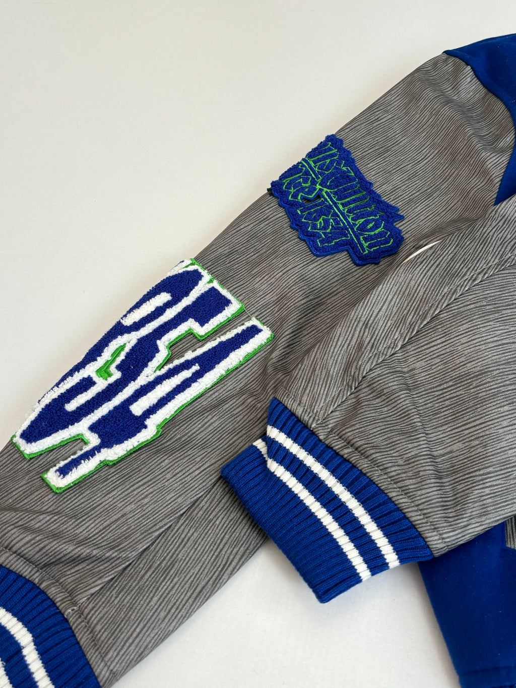 Long-sleeve top, grey knit with blue striped cuffs and large embroidered emblem