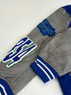 Long-sleeve top, grey knit with blue striped cuffs and large embroidered emblem