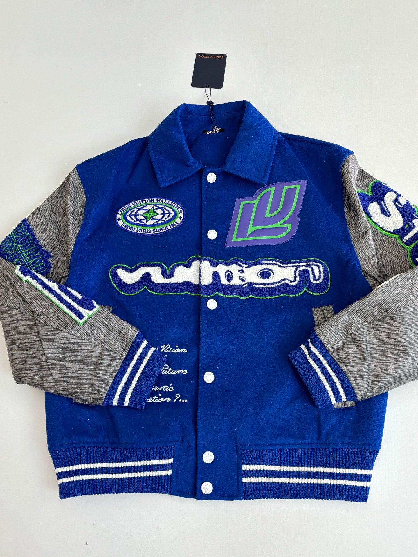 Blue varsity jacket with colorful front patches, button front, striped cuffs and hem