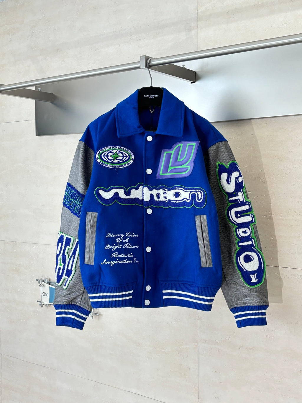Blue varsity jacket with gray sleeves, button front, striped ribbed cuffs
