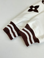 White long-sleeve top with brown striped cuffs and flower appliques