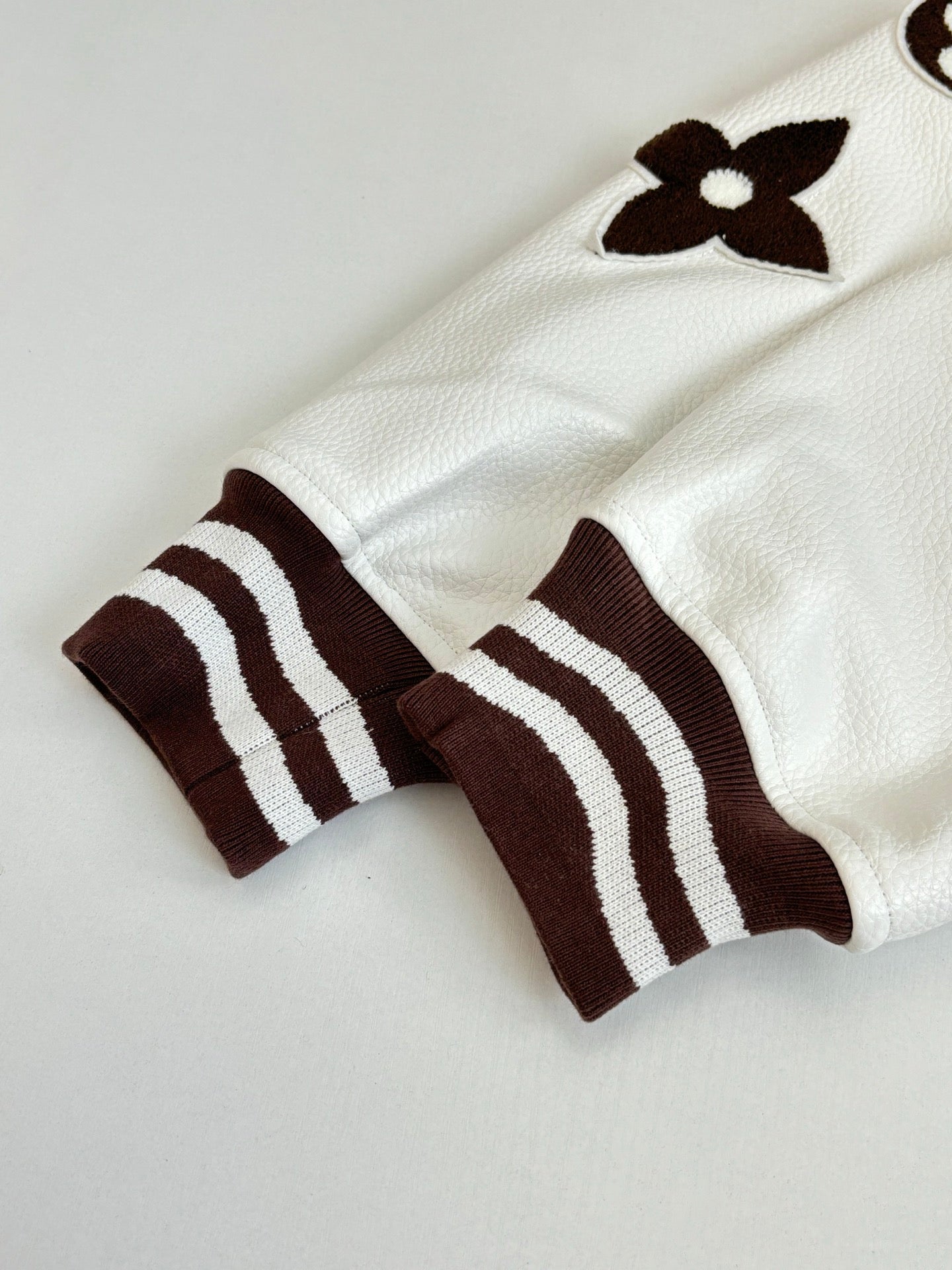 White long-sleeve top with brown striped cuffs and flower appliques
