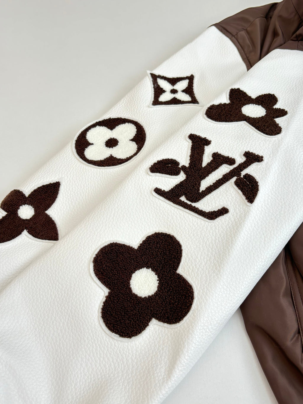 White long-sleeve top with brown graphic logos and floral motifs
