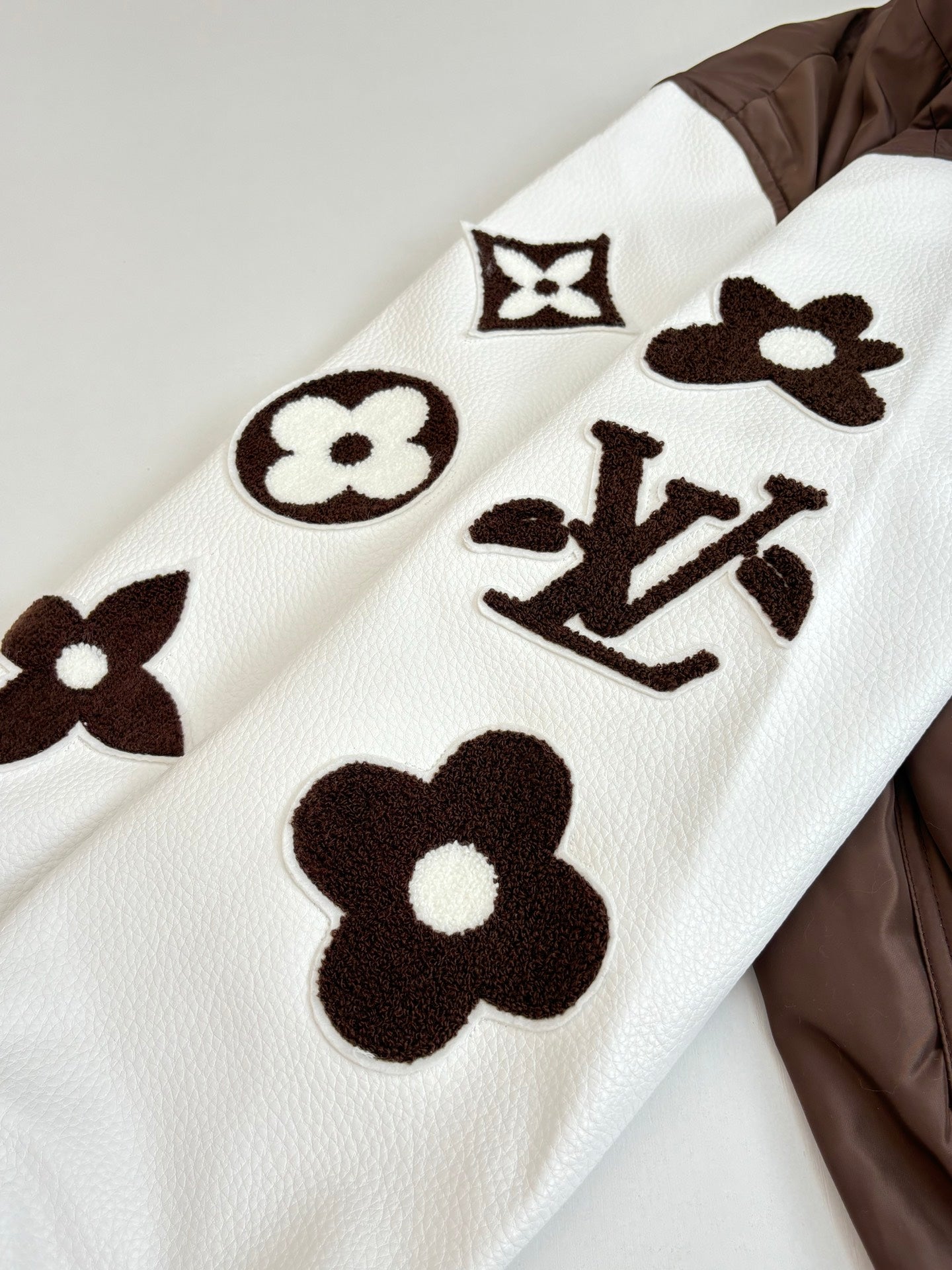 White long-sleeve top with brown graphic logos and floral motifs