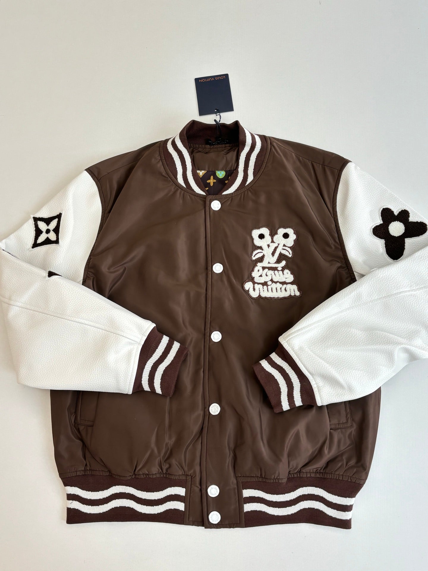 Louis Vuitton brown long jacket with white sleeves, striped cuffs, and front logo patch