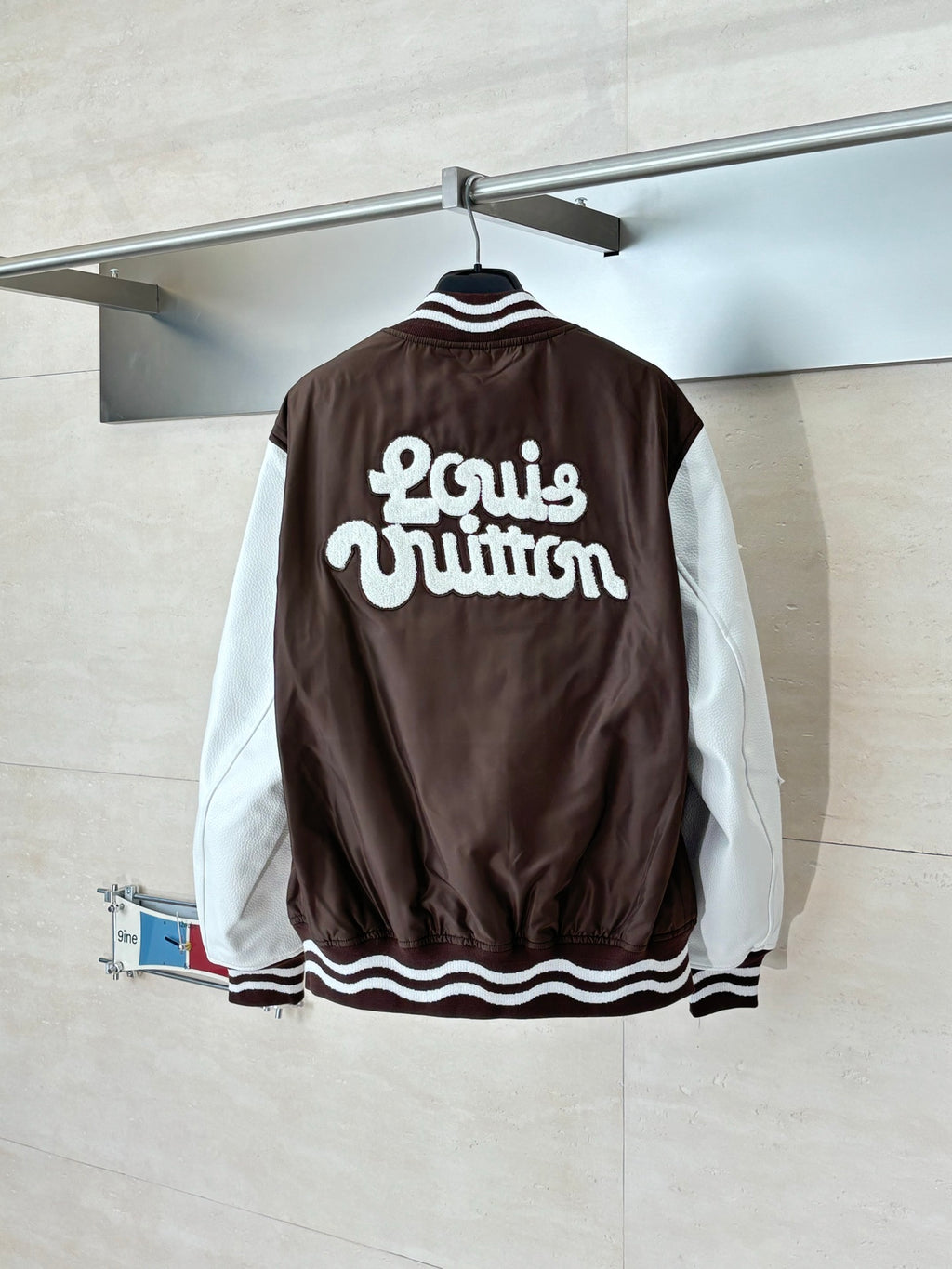 Louis Vuitton brown long jacket back with bold “Louis Vuitton” lettering and striped trim
