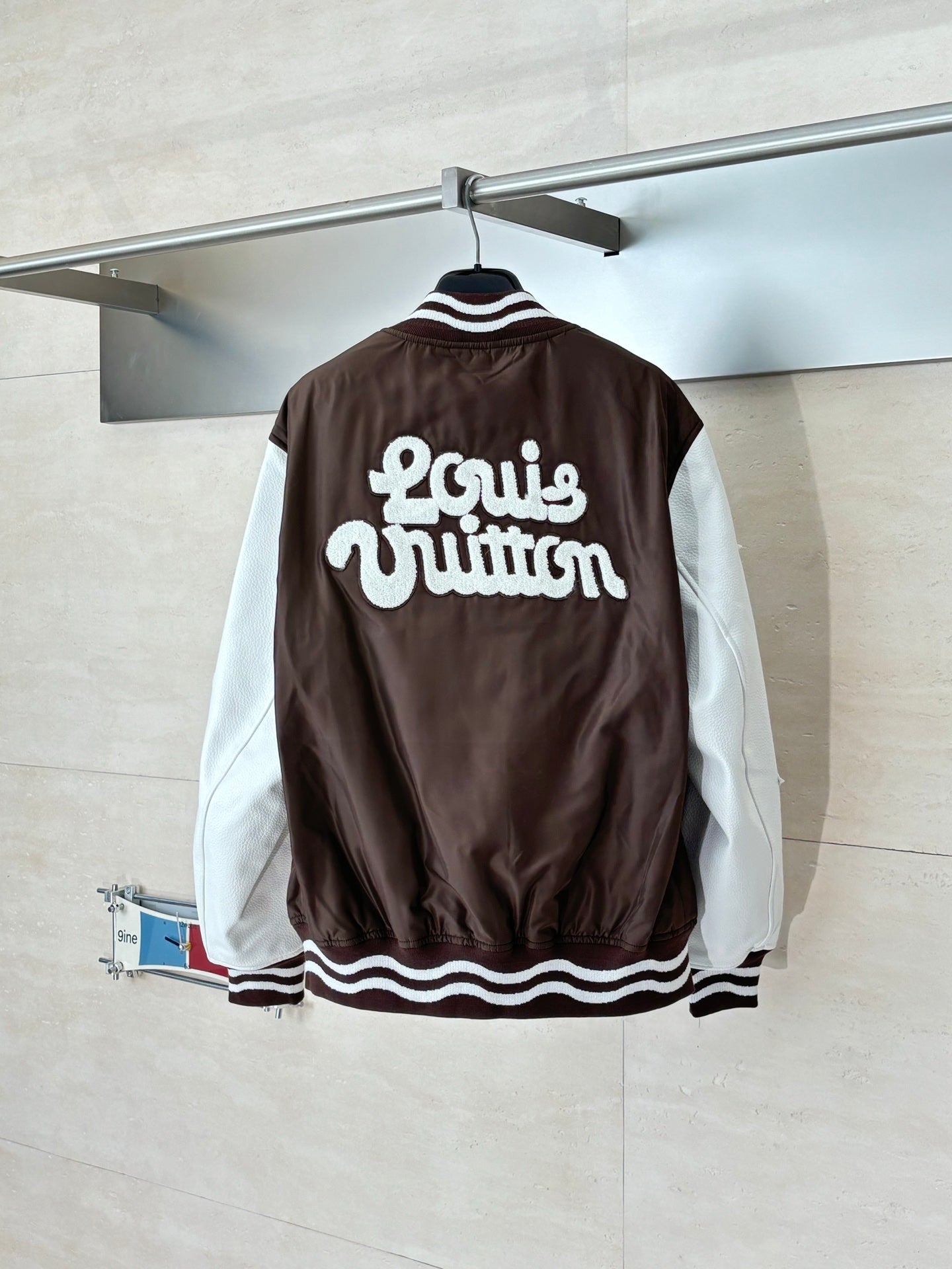 Louis Vuitton brown long jacket back with bold “Louis Vuitton” lettering and striped trim