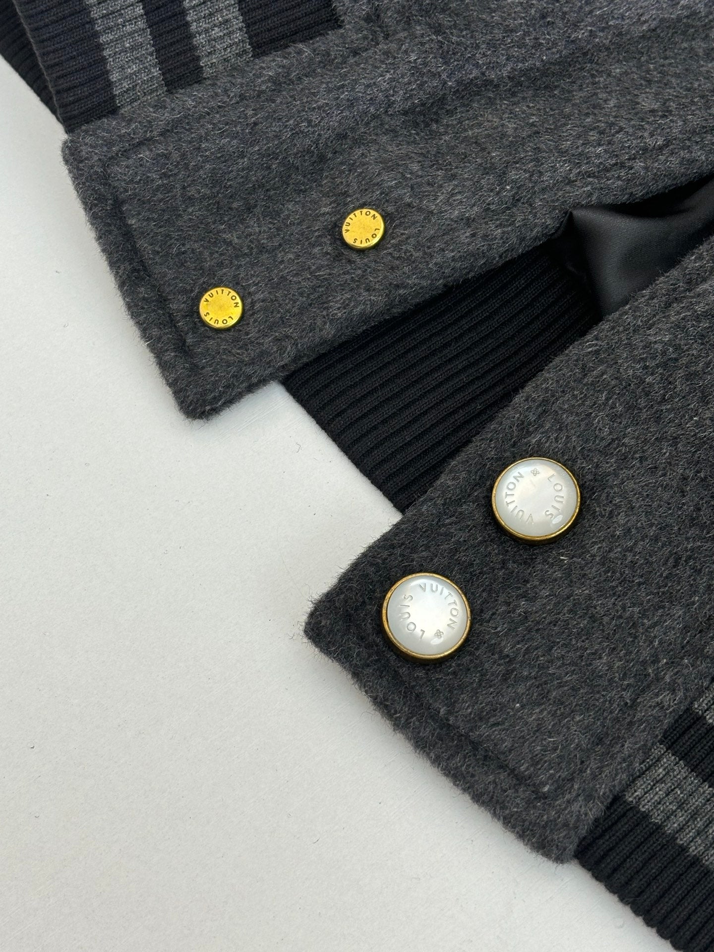 Dark gray wool varsity jacket cuff detail with snap buttons and ribbed stripes