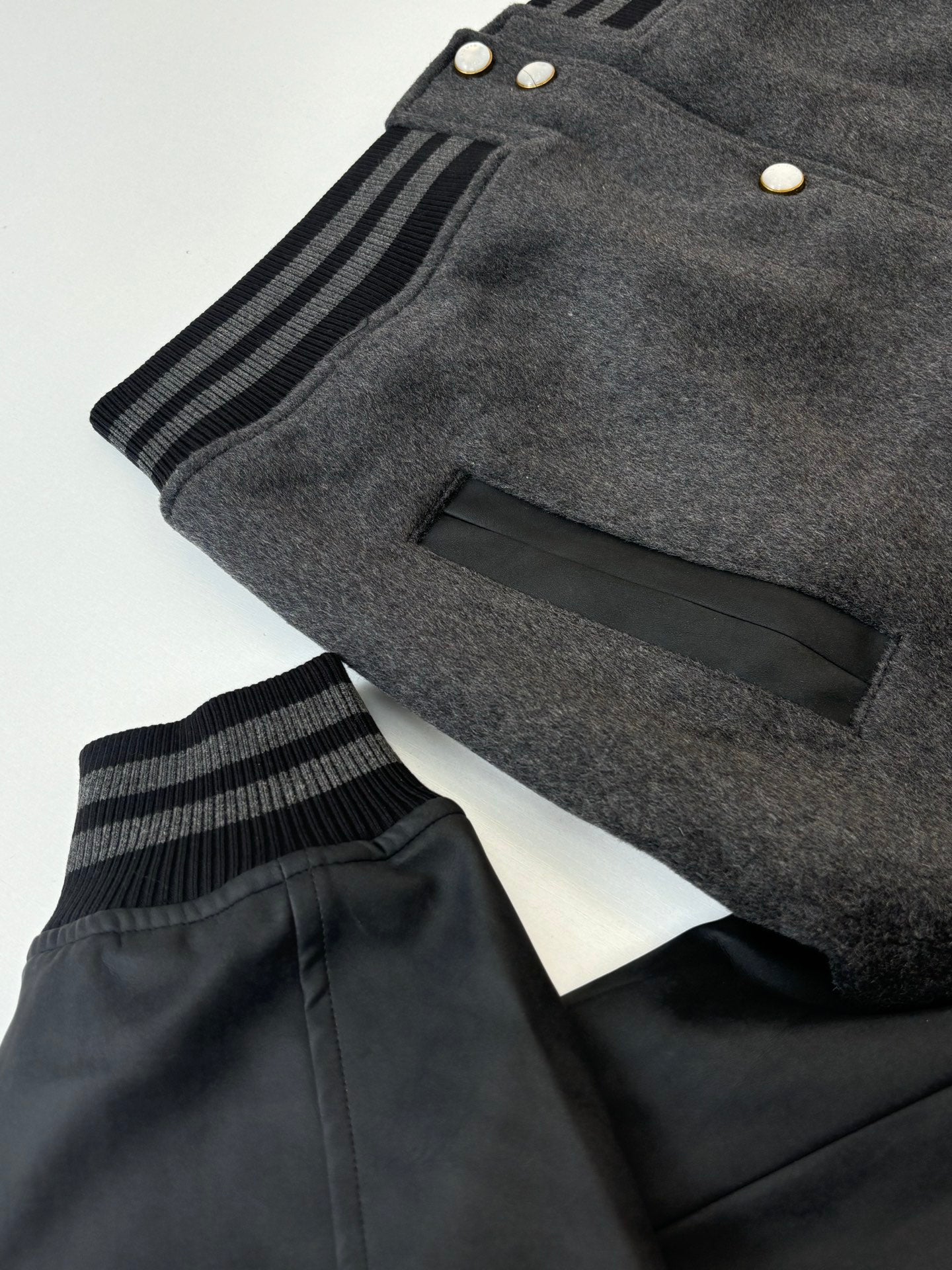 Dark gray wool varsity jacket with black sleeves and striped ribbed cuff